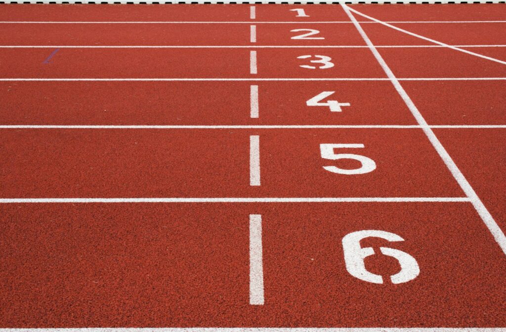 An empty red athletics track with white lane lines and lane numbers