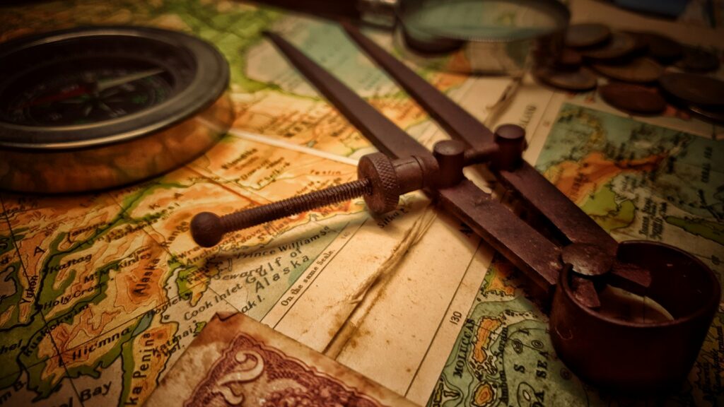 A pair of brass dividers resting on an old paper map