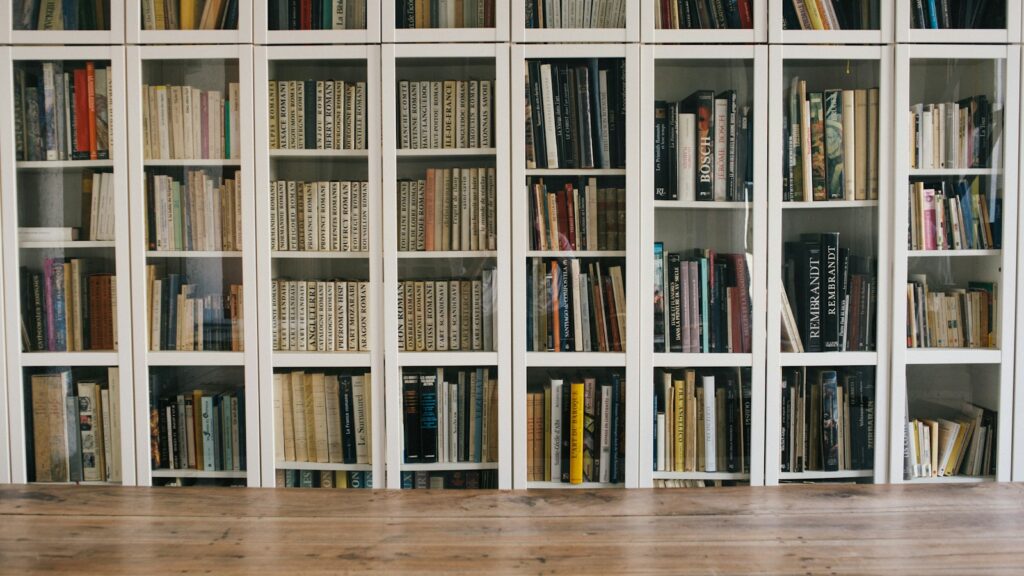 Books on white shelves with an empty space along the bottom shelf