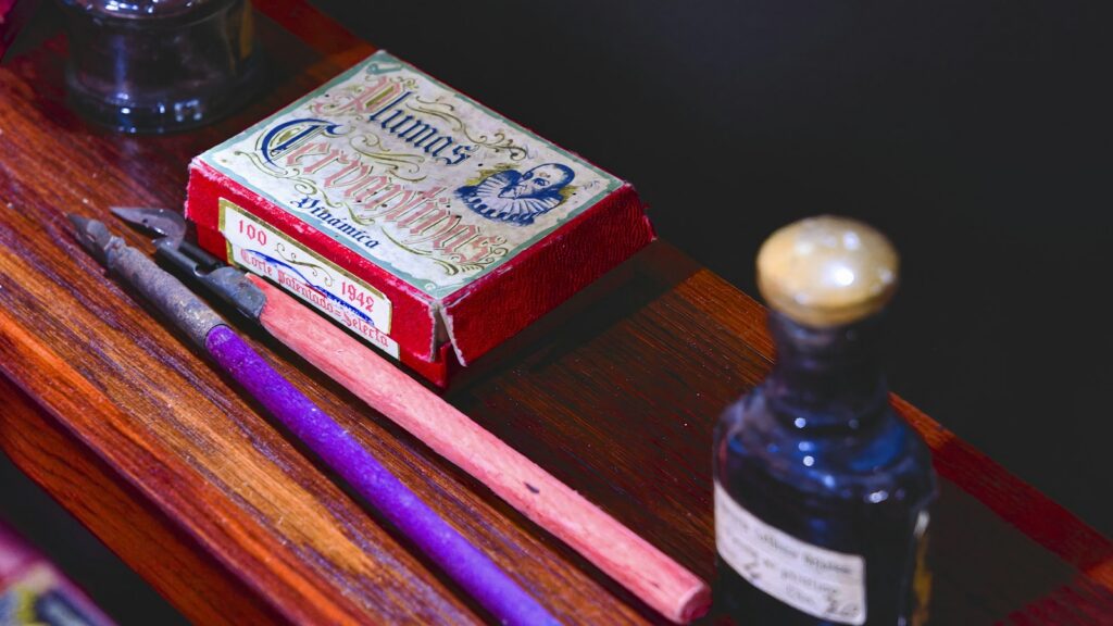 A wooden table with a bottle of ink and a pair of scissors