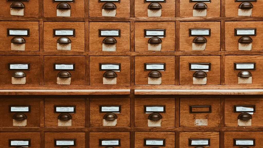 A wall of labelled wooden card catalog drawers in a library